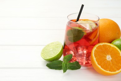 Photo of Tasty punch with ice, mint and slices of fruits in glass on white wooden table, closeup with space for text. Refreshing drink