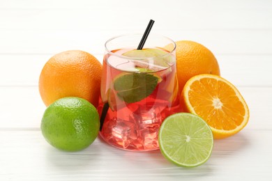 Photo of Tasty punch with ice, mint and slices of fruits in glass on white wooden table, closeup. Refreshing drink