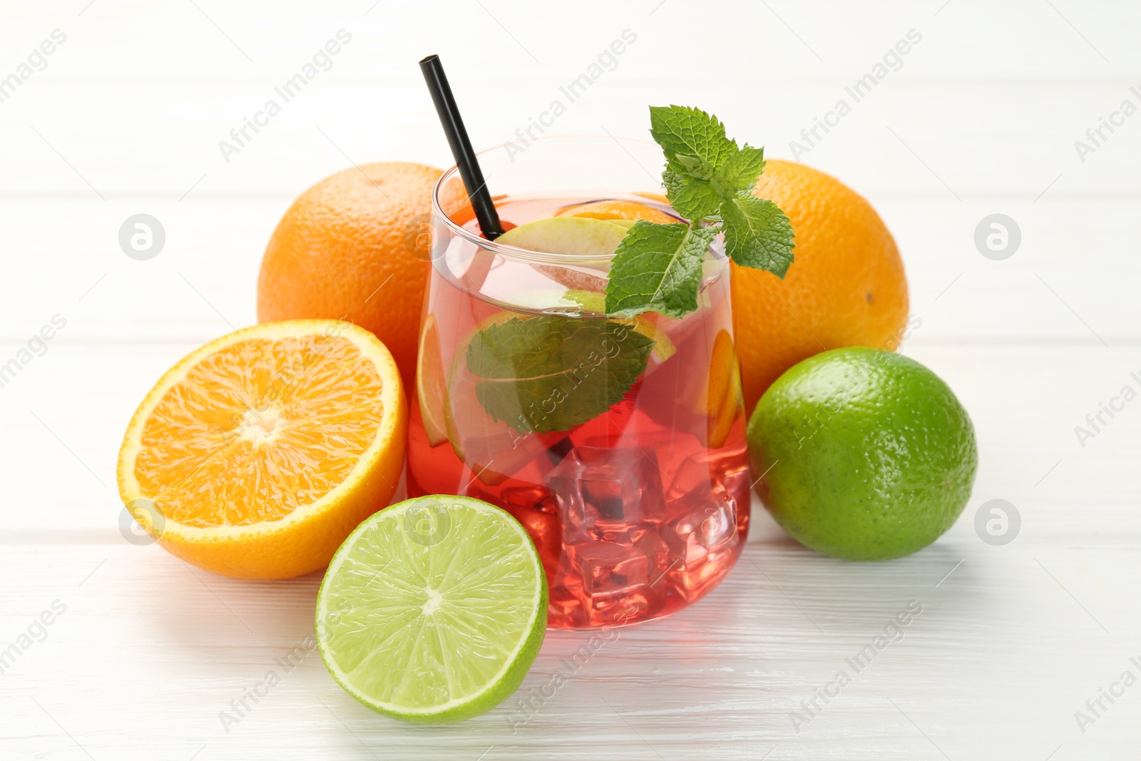 Tasty punch with ice, mint and slices of fruits in glass on white wooden table, closeup. Refreshing drink Photo of Tasty punch with ice, mint and slices of fruits in glass on white wooden table, closeup. Refreshing drink