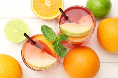 Photo of Tasty punch with mint and slices of fruits in glasses on white wooden table, flat lay. Refreshing drink