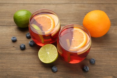 Photo of Tasty punch with fruits and blueberries on wooden table, closeup. Refreshing drink
