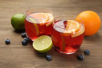 Photo of Tasty punch with fruits and blueberries on wooden table, closeup. Refreshing drink