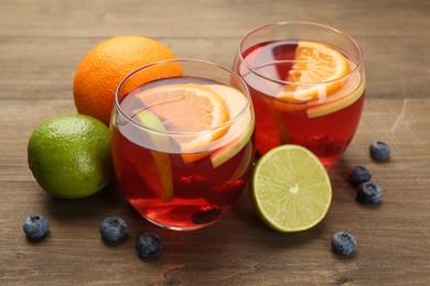 Photo of Tasty punch with fruits and blueberries on wooden table, closeup. Refreshing drink
