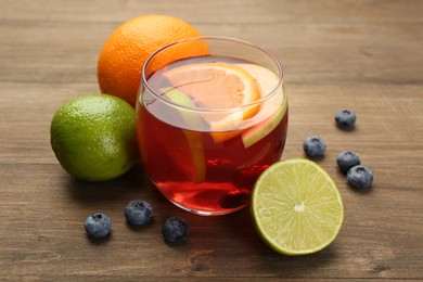 Photo of Tasty punch with fruits and blueberries on wooden table, closeup. Refreshing drink