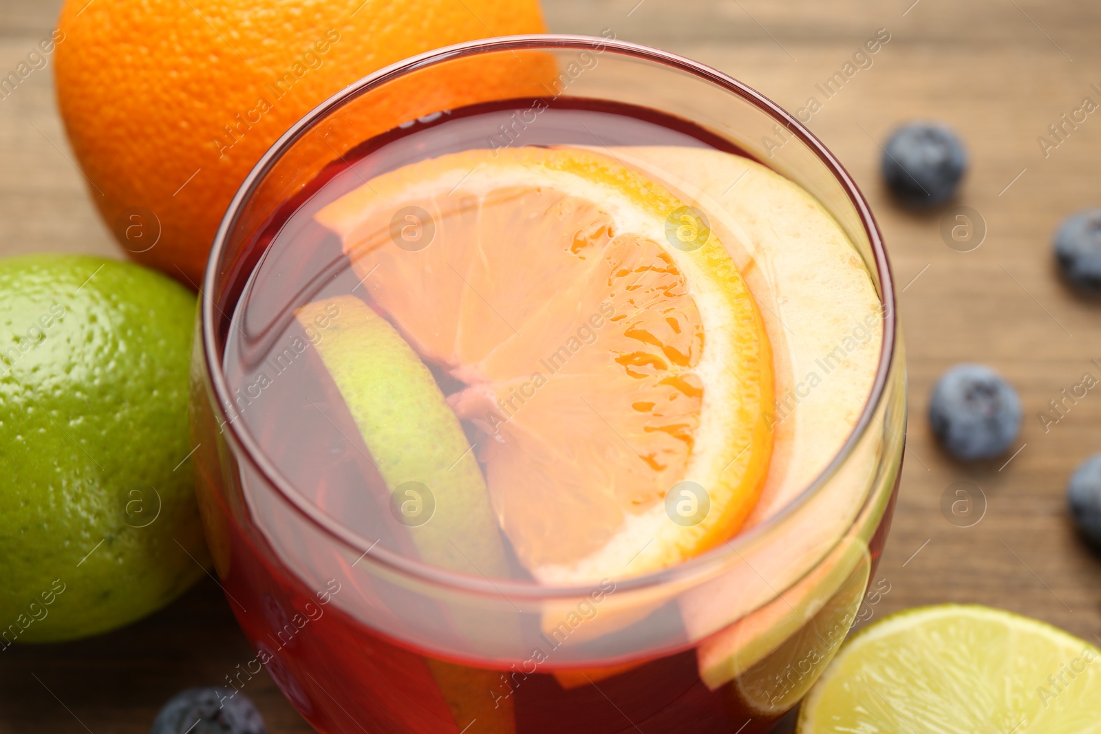 Photo of Tasty punch with fruits and blueberries on wooden table, closeup. Refreshing drink