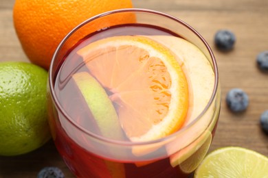 Photo of Tasty punch with fruits and blueberries on wooden table, closeup. Refreshing drink
