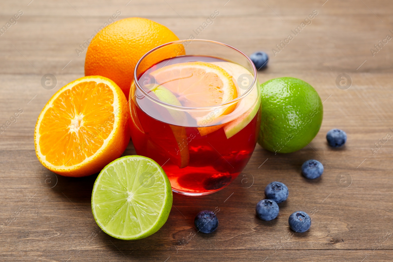 Photo of Tasty punch with fruits and blueberries on wooden table, closeup. Refreshing drink