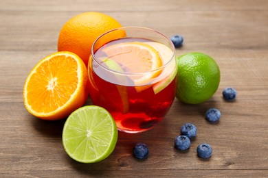 Photo of Tasty punch with fruits and blueberries on wooden table, closeup. Refreshing drink