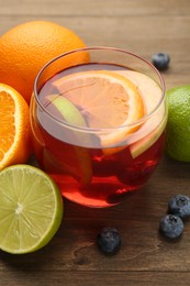 Photo of Tasty punch with fruits and blueberries on wooden table, closeup. Refreshing drink