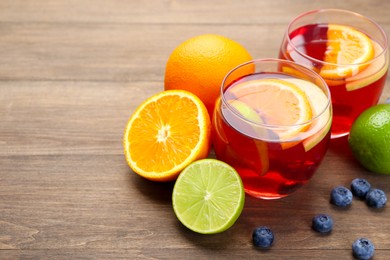Photo of Tasty punch with fruits and blueberries on wooden table, closeup with space for text. Refreshing drink