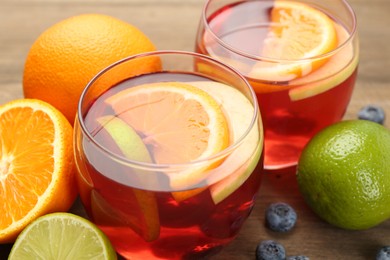 Photo of Tasty punch with fruits and blueberries on wooden table, closeup. Refreshing drink