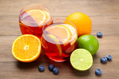 Photo of Tasty punch with fruits and blueberries on wooden table, closeup. Refreshing drink