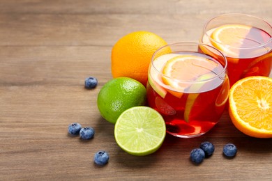Photo of Tasty punch with fruits and blueberries on wooden table, closeup with space for text. Refreshing drink