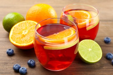Photo of Tasty punch with fruits and blueberries on wooden table, closeup. Refreshing drink
