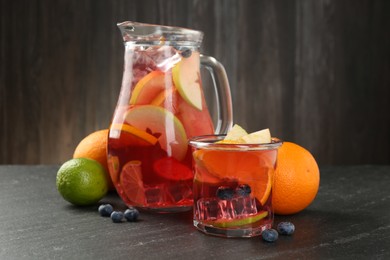Photo of Tasty punch, fruits and berries on dark gray textured table