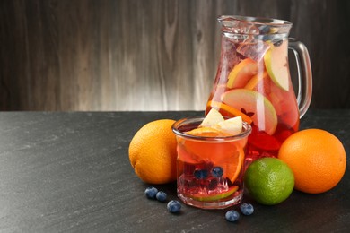 Photo of Tasty punch, fruits and berries on dark gray textured table. Space for text
