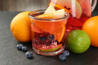 Photo of Tasty punch, fruits and berries on dark gray textured table, closeup