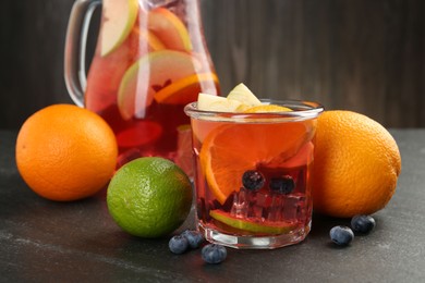 Photo of Tasty punch, fruits and berries on dark gray textured table, closeup
