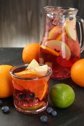Photo of Tasty punch, fruits and berries on dark gray textured table, closeup