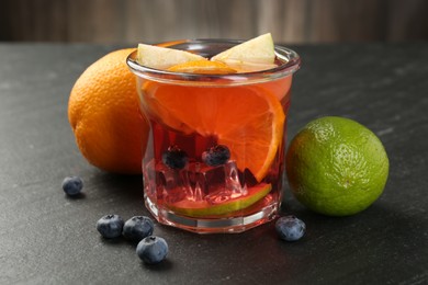 Photo of Tasty punch, fruits and berries on dark gray textured table, closeup