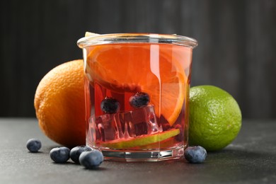 Photo of Tasty punch, fruits and berries on dark gray textured table, closeup