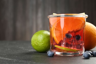 Photo of Tasty punch, fruits and berries on dark gray textured table, closeup. Space for text