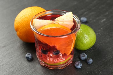 Photo of Tasty punch, fruits and berries on dark gray textured table, closeup