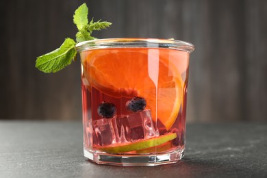 Photo of Tasty fruity punch in glass on dark gray textured table, closeup