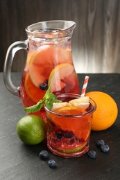 Photo of Tasty punch, fruits and berries on dark gray textured table