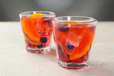Photo of Tasty fruity punch in glasses on light gray textured table, closeup
