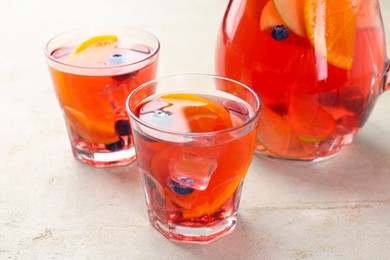 Photo of Tasty fruity punch on light gray textured table, closeup