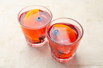 Photo of Tasty fruity punch in glasses on light gray textured table, closeup