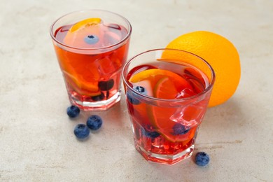 Photo of Tasty fruity punch in glasses on light gray textured table, closeup