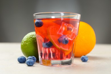 Photo of Tasty punch, fruits and berries on light gray textured table, closeup