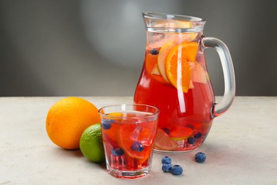 Photo of Tasty punch, fruits and berries on light gray table