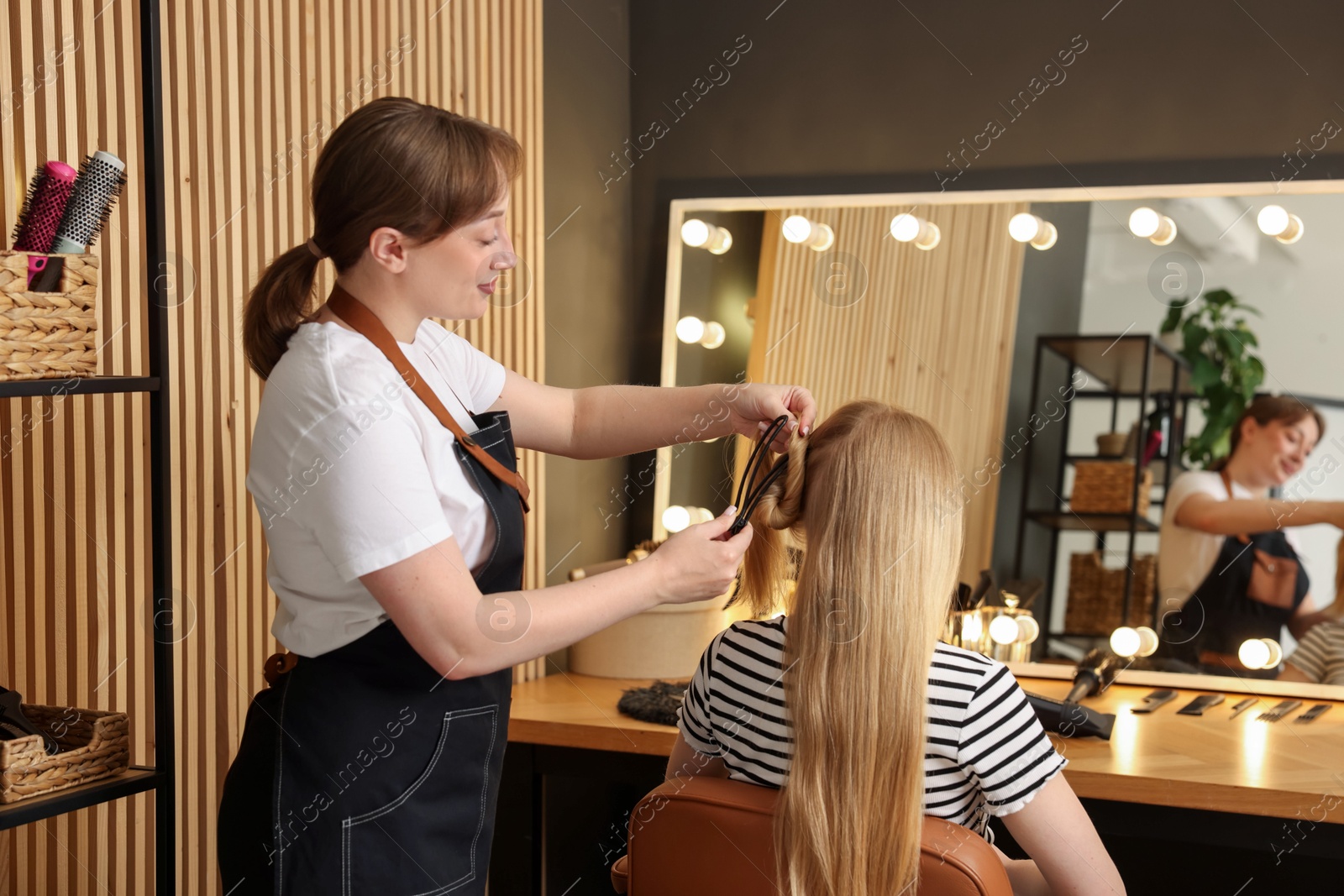 Photo of Professional hairstylist working with client in salon