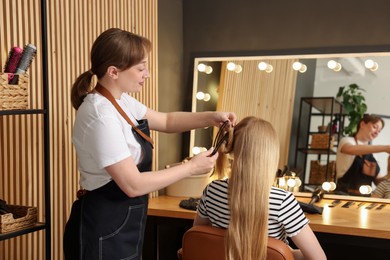 Photo of Professional hairstylist working with client in salon