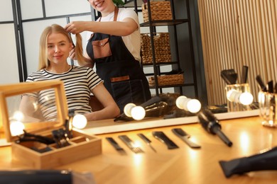 Photo of Professional hairstylist working with client in salon, closeup