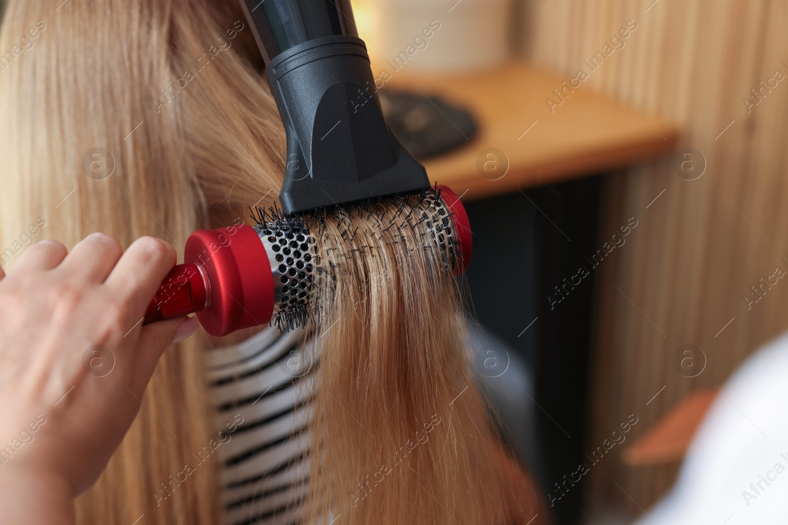 Photo of Hairstylist blow drying client's hair in salon, closeup. Space for text