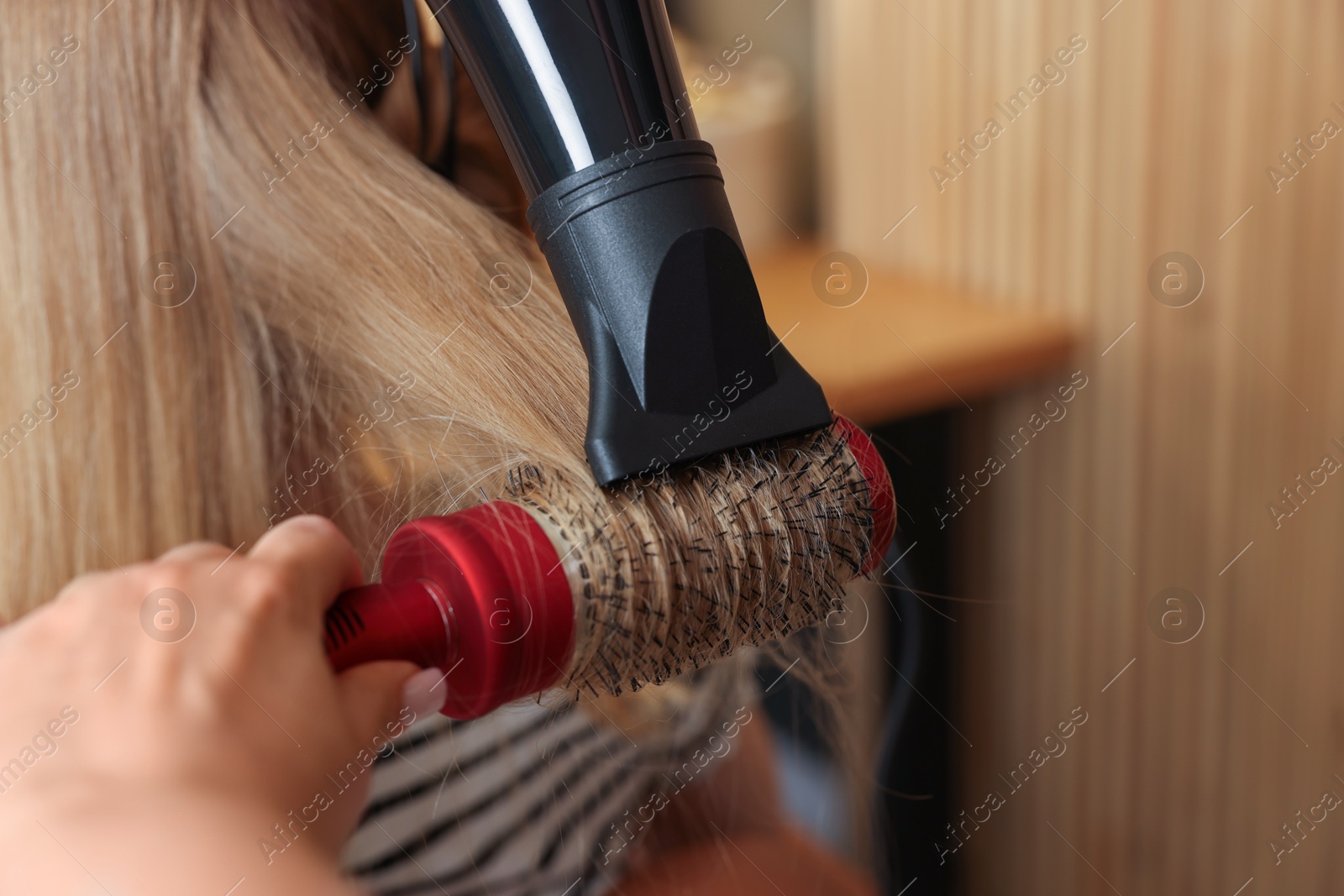 Photo of Hairstylist blow drying client's hair in salon, closeup. Space for text