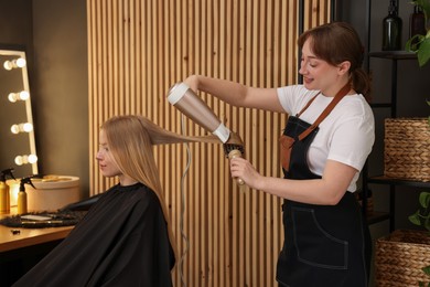 Photo of Hairstylist blow drying client's hair in salon