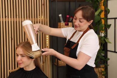 Photo of Hairstylist blow drying client's hair in salon