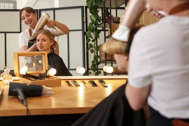 Photo of Hairstylist blow drying client's hair in salon