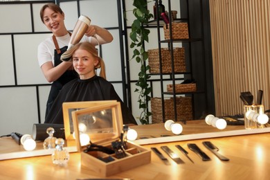 Photo of Hairstylist blow drying client's hair in salon
