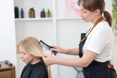 Photo of Professional hairstylist combing woman's hair in salon