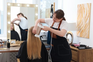 Photo of Hairstylist blow drying client's hair in salon
