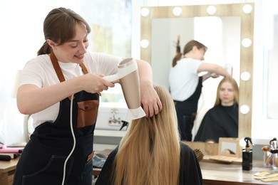 Photo of Hairstylist blow drying client's hair in salon