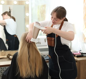 Photo of Hairstylist blow drying client's hair in salon