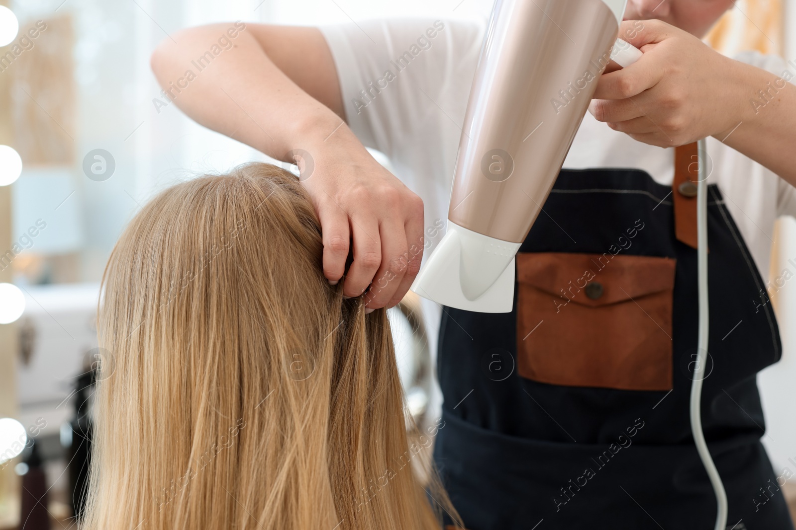 Hairstylist blow drying client's hair in salon, closeup Photo of Hairstylist blow drying client's hair in salon, closeup