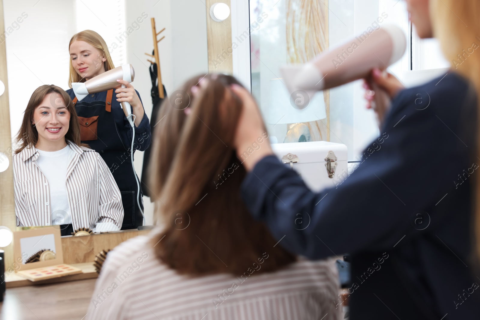 Hairstylist blow drying client's hair in salon, closeup Photo of Hairstylist blow drying client's hair in salon, closeup